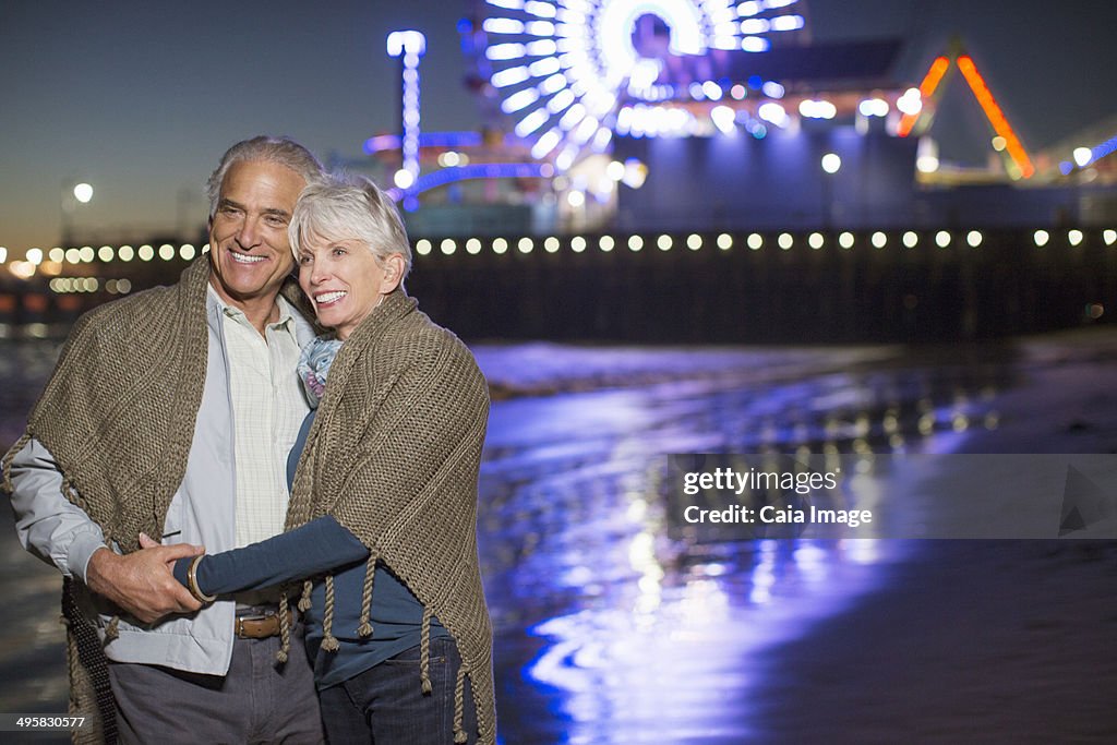 Senior couple hugging on beach at night