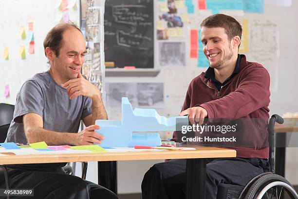 engineering instructor with aspergers discussing 3d shape with student in a wheelchair with a spinal cord injury - autismus stock pictures, royalty-free photos & images