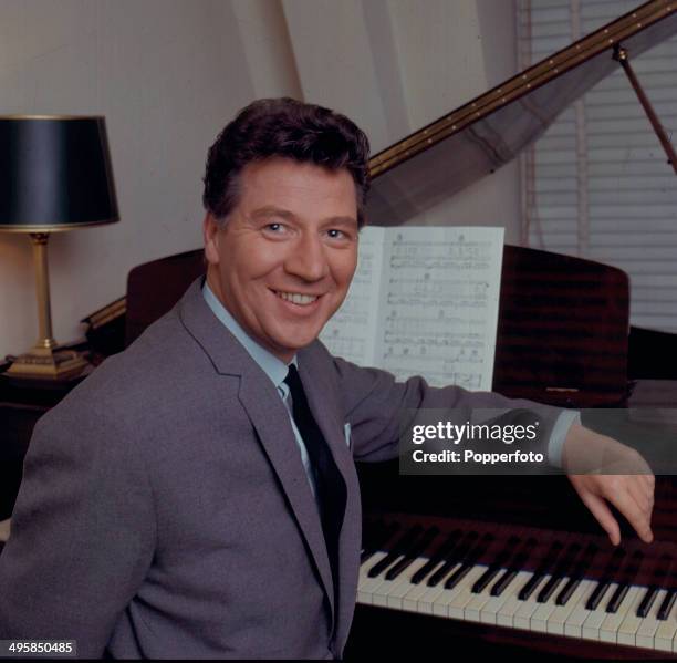 English comedian and singer Max Bygraves posed sitting at a grand piano in 1967.