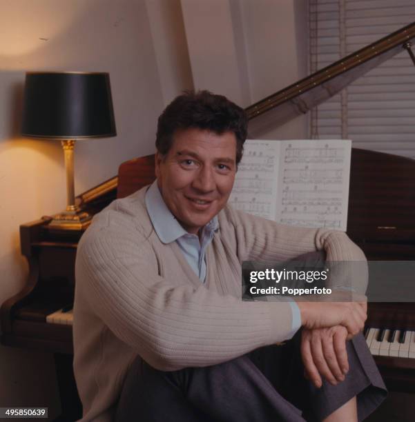 English comedian and singer Max Bygraves posed sitting at a grand piano in 1967.