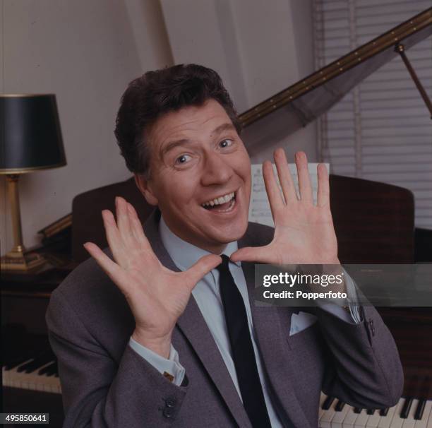 English comedian and singer Max Bygraves posed sitting at a grand piano in 1967.