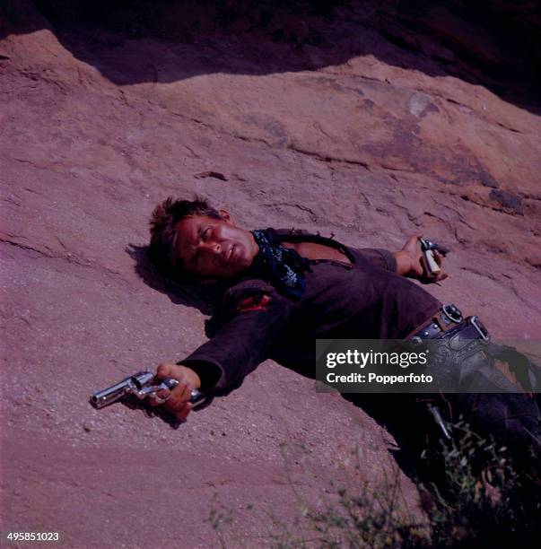 American actor Robert Conrad pictured holding a revolver in each hand on the set of the television series 'The Wild Wild West' in 1968.