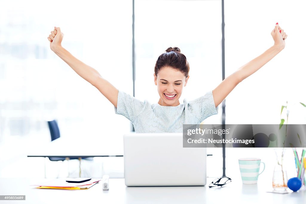 Entrepreneur With Laptop Celebrating Success At Desk