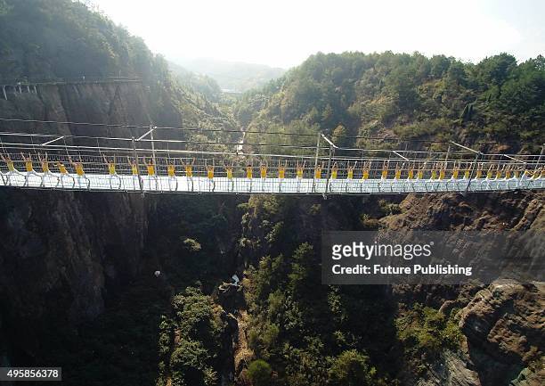 Yoga enthusiasts perform on a suspension bridge with a glass floor in a scenic zone on November 05, 2015 in Pingjiang, China. The bridge has about...