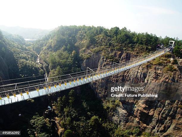 Yoga enthusiasts perform on a suspension bridge with a glass floor in a scenic zone on November 05, 2015 in Pingjiang, China. The bridge has about...