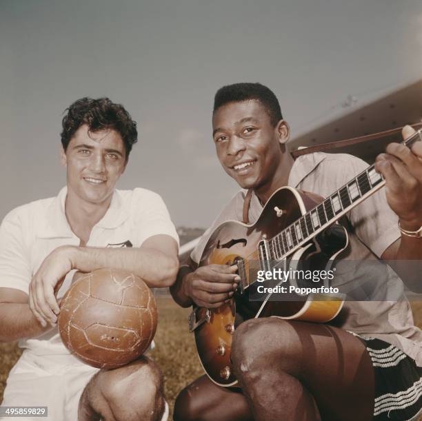 Brazilian footballer Pele posed holding a guitar beside French singer Sacha Distel holding a football circa 1965.