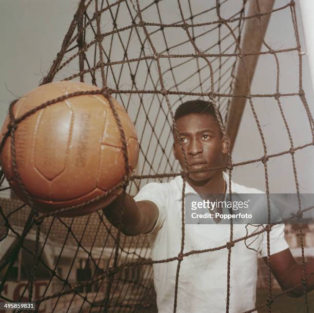 Brazilian footballer Pele wearing a Santos FC shirt retrieves a ball from the goal net circa 1960.