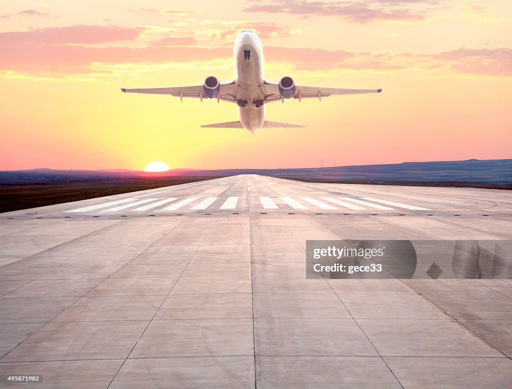 Passenger airplane taking off at sunset