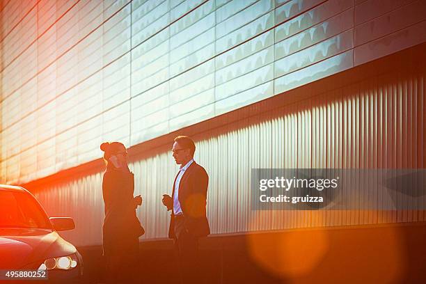 fashionable business couple in talk at the street beside car - twilights stockfoto's en -beelden