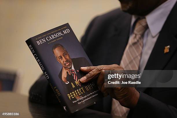 Republican presidential candidate Ben Carson holds his book as he signs it at an event in a Barnes and Noble store on November 5, 2015 in Fort...