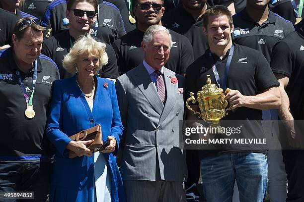 New Zealand's All Blacks rugby team captain Richie McCaw holds the Webb Ellis Cup as he stands with Britain's Prince Charles and his wife Camilla,...