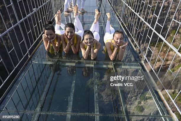 Yoga enthusiasts practice on a glass suspension bridge at the Shiniuzhai National Geological Park on November 5, 2015 in Pingjiang County, Yueyang...