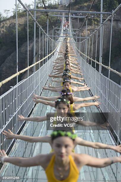 Yoga enthusiasts practice on a glass suspension bridge at the Shiniuzhai National Geological Park on November 5, 2015 in Pingjiang County, Yueyang...