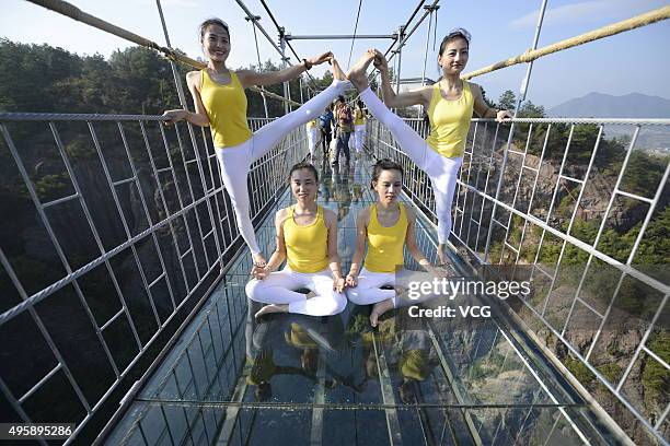 Yoga enthusiasts practice on a glass suspension bridge at the Shiniuzhai National Geological Park on November 5, 2015 in Pingjiang County, Yueyang...