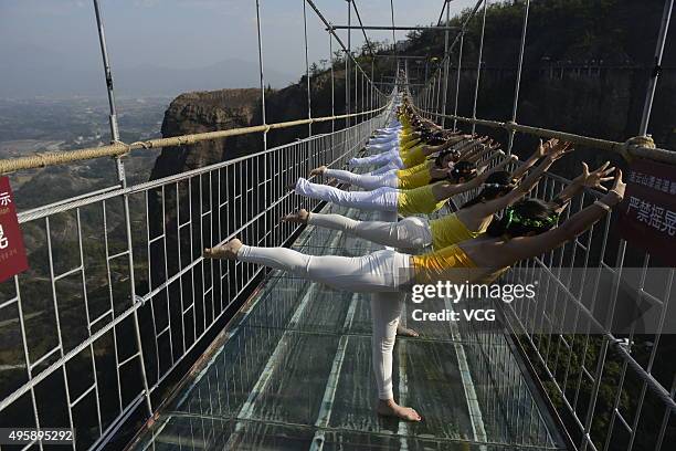 Yoga enthusiasts practice on a glass suspension bridge at the Shiniuzhai National Geological Park on November 5, 2015 in Pingjiang County, Yueyang...