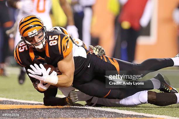 Tyler Eifert of the Cincinnati Bengals dives past Tashaun Gipson of the Cleveland Browns to score a touchdown during the first quarter at Paul Brown...