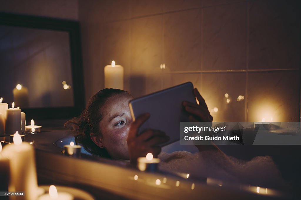 Woman using tablet pc in bathtub.