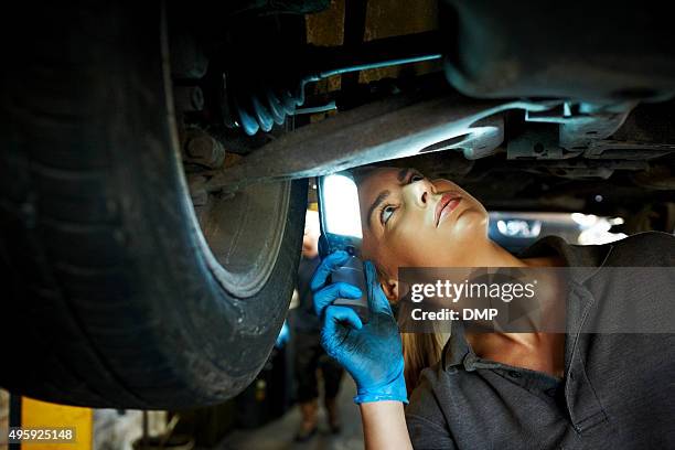 female mechanic inspecting a lifted car - auto mechanic stock pictures, royalty-free photos & images