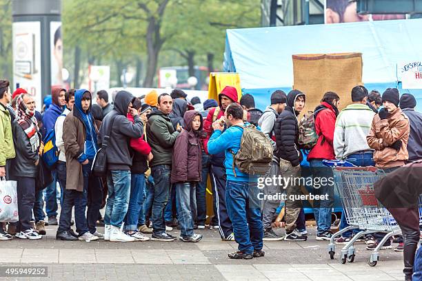 refugees standing in a row - immigrants stockfoto's en -beelden