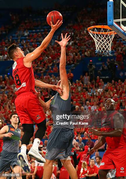 Jarrod Kenny of the Wildcats lays up against Mitch Young of the Crocodiles during the round five NBL match between Perth Wildcats and Townsville...