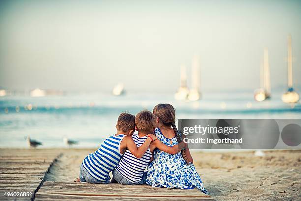 niños de descanso en la playa en el atardecer y abrazar - niño cuatro años fotografías e imágenes de stock