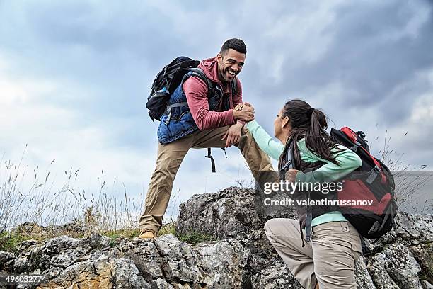 homem e mulher a ajuda on the rocks - clambering imagens e fotografias de stock