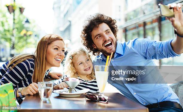 cheerful family sitting in a restaurant outdoors and making selfie. - children restaurant stockfoto's en -beelden