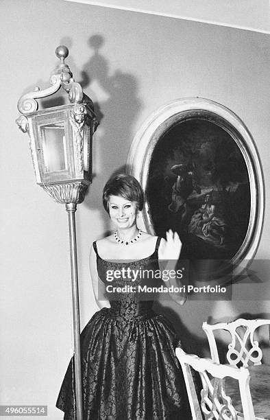 Italian actress Sophia Loren posing smiling with one hand raised in her new house located in the well-known Palazzo Lovatelli. She wears Bulgari...