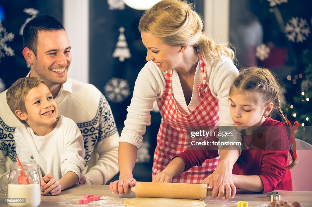 Family of four baking Christmas cookies together