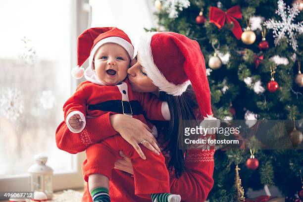 mutter, küssen ihr baby im the christmas tree - baby christmas stock-fotos und bilder