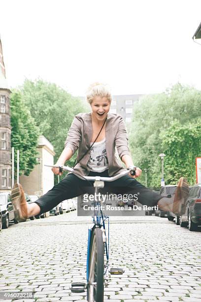 young woman having fun riding her bike in city streets - vitaliteit fiets stockfoto's en -beelden