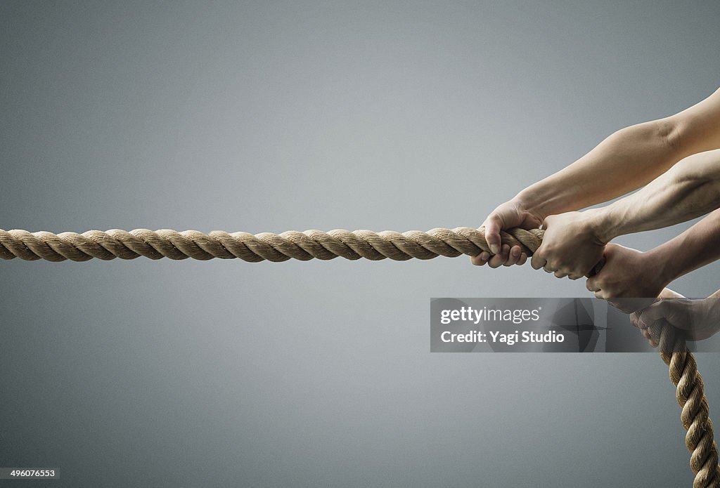 The hands of two men pulling the rope