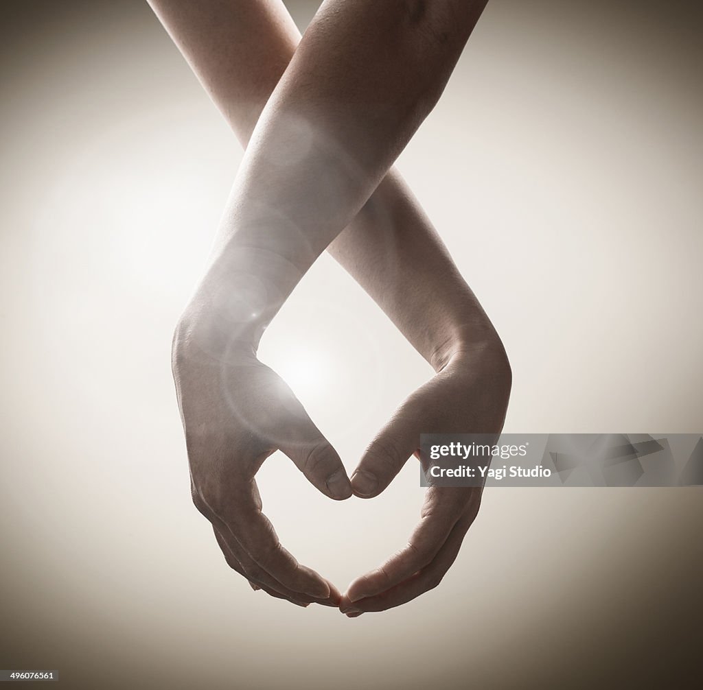 Hands of two people mading ??the shape of heart