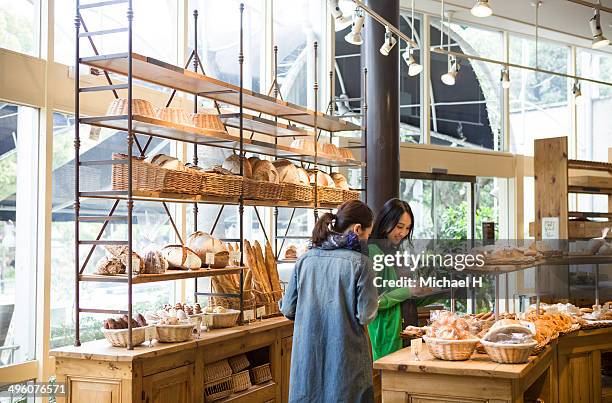 female friends chosing breads in bakeryshop. - ケーキ屋 ストックフォトと画像
