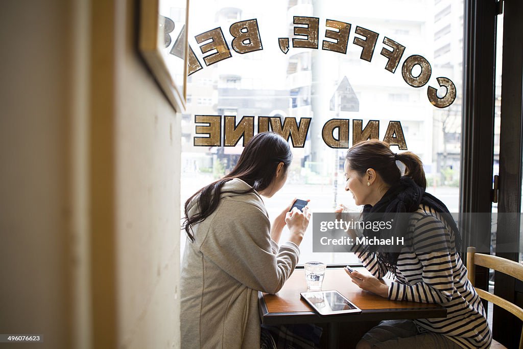 Friends talking with smartphones at  cafe