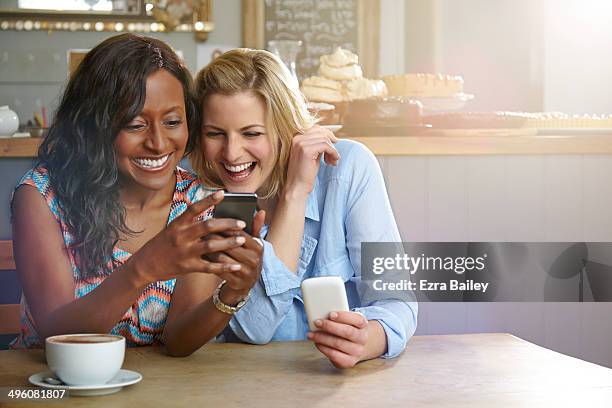 friends laughing at a phone in a coffee shop - friends sharing bildbanksfoton och bilder