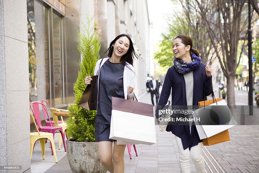 Two female friends walking with shopping bags