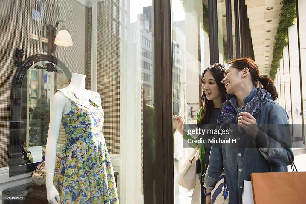 Two smiling female friends window shopping