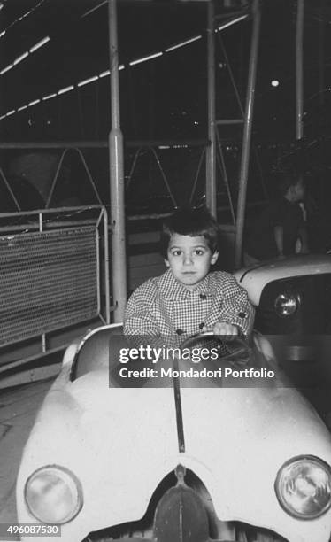 Italian television host and actress Barbara D'Urso at age of three, on board a car in a merry-go-round. Italy, 1960