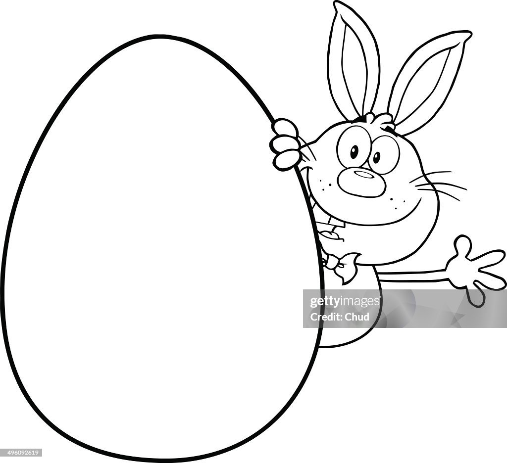 Black and white rabbit waving behind easter egg