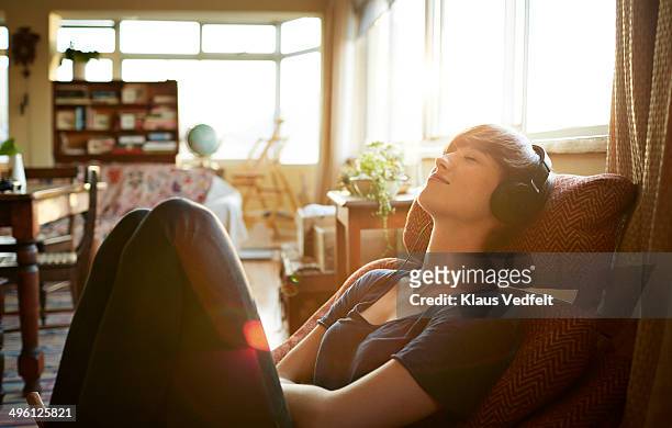 young woman relaxing with headphones at home - gelassene person stock-fotos und bilder
