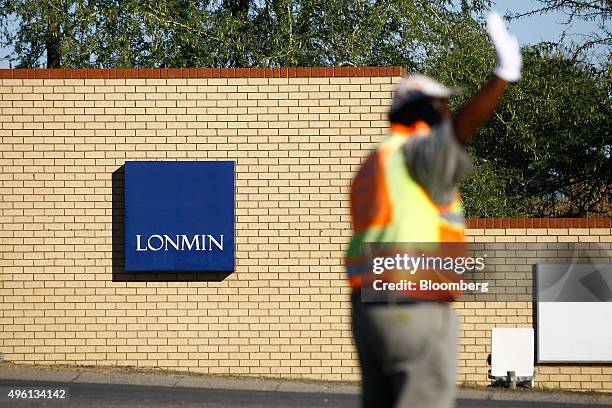 Signage sits on the wall as a safety official directs traffic at the Marikana mine, operated by Lonmin Plc, in Marikana, South Africa, on Friday,...