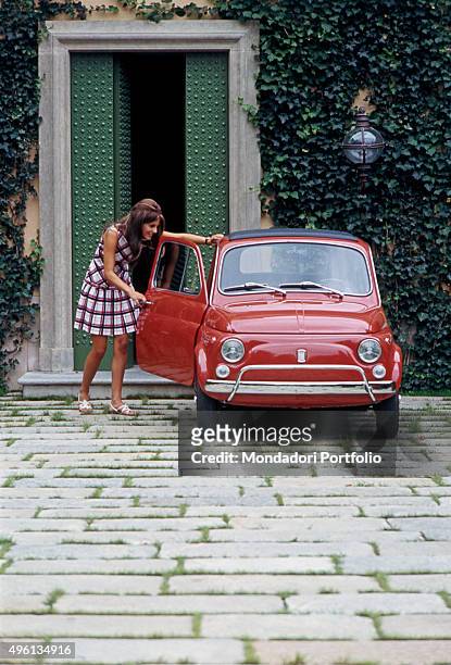 Girl opening the door of a Fiat 500 L. Italy, 1968