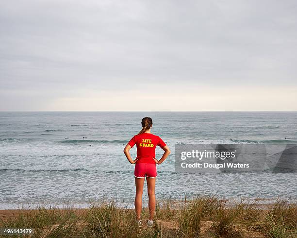 female lifeguard watching surfers at sea. - lifeguard stock pictures, royalty-free photos & images