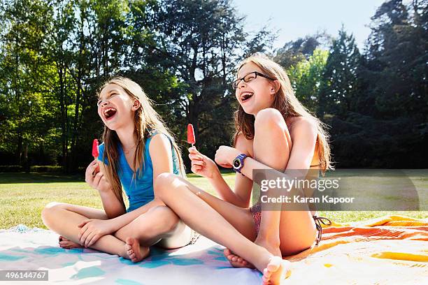 girls laughing with ice lolly - young girl swimsuit stockfoto's en -beelden