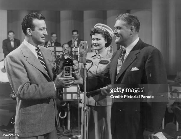 Musician Harry James being presented with an award for 'Band of the Year' by PBS representatives, circa 1945-1950.