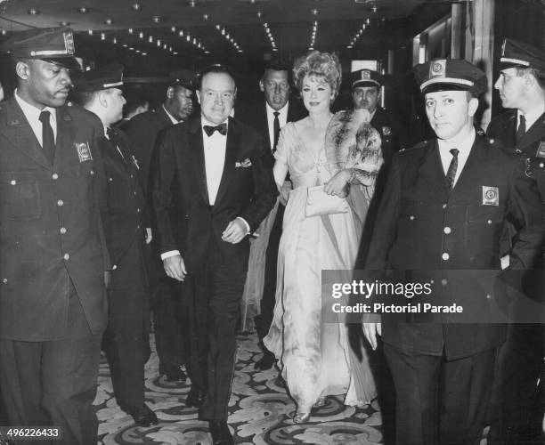 Entertainer Bob Hope and comedian Lucille Ball, flanked by policemen as they arrive at the theater to promote the film 'Critic's Choice', 1963.