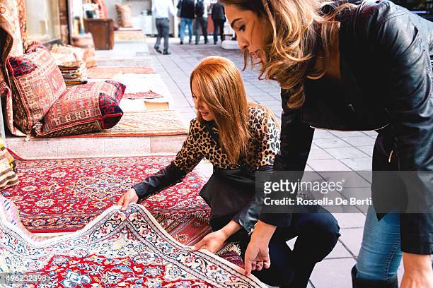 two cheerful women buying carpets - perzisch tapijt stockfoto's en -beelden