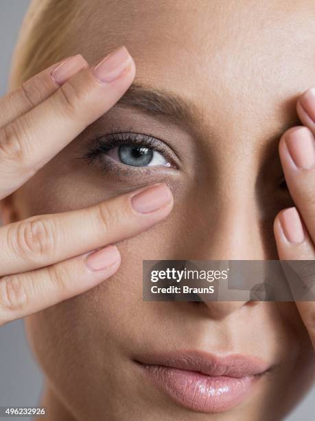 close up of a woman peeking through her hands. - hands covering eyes stock pictures, royalty-free photos & images