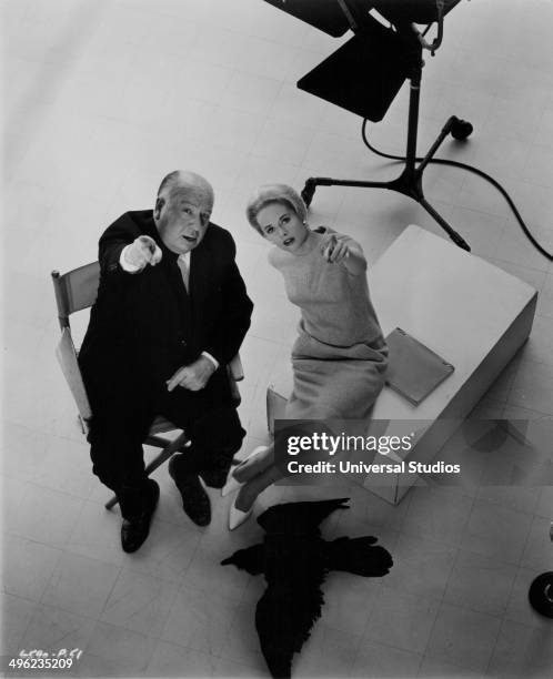 Posed portrait of director Alfred Hitchcock and actress Tippi Hedren pointing up towards the camera, on the set of the movie 'The Birds', 1963.